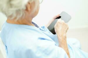 Asian senior woman wearing eyeglasses or vision glasses using a smartphone at home care service. photo