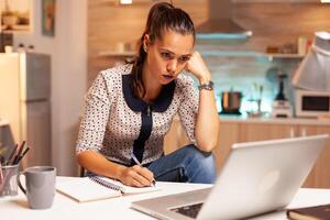 Concentrated businesswoman trying to finish a project for work during midnight. Employee using modern technology at midnight doing overtime for job, business, busy, career, network, lifestyle ,wireless. photo