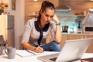 concentrado mujer de negocios molesto a terminar un proyecto para trabajo durante medianoche. empleado utilizando moderno tecnología a medianoche haciendo tiempo extraordinario para trabajo, negocio, ocupado, carrera profesional, red, estilo de vida ,inalámbrico. foto