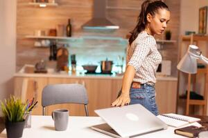 Entrepreneur woman closing laptop after finishing a project before deadline in home. Employee using modern technology at midnight doing overtime for job, business, busy, career, network, lifestyle ,wireless. photo
