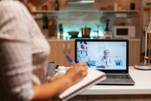 Doctor explaining diagnosis during a video conference with patient at midnight. Physician giving consultation to sick patient from hospital office during virtual examination, screen, medicine, appointment. photo