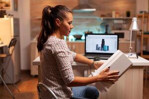 Serious architect working on a housing project holding a building model during late night time. Engineer artist creating and working in office holding scale building model, determination, career. photo