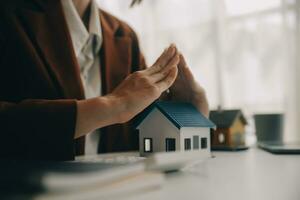 Real estate broker agent presenting and consult to customer to decision making sign insurance form agreement, buy and sell home model, concerning mortgage loan offer for and house insurance photo