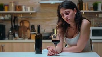 Lonely woman holding a glass of red wine. Unhappy person suffering of migraine, depression, disease and anxiety feeling exhausted with dizziness symptoms having alcoholism problems. photo