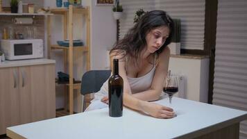 Deprimido mujer Bebiendo un vaso de vino solo en cocina. infeliz persona sufrimiento de migraña, depresión, enfermedad y ansiedad sensación agotado con mareo síntomas teniendo alcoholismo problemas. foto