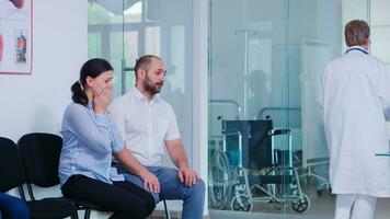 Young wife crying after hearing doctor bad news in hospital waiting room. Doctor giving unfavorable test results. Stressed man and woman during medic appointment. photo