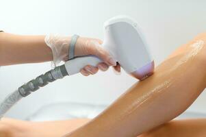 close-up of young caucasian slender woman getting laser epilation in beauty salon. photo