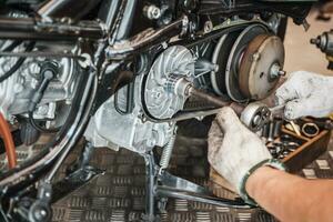 Mechanic using wrench and socket to Remove auto Transmission system or Rear Clutch Pulley of scooter Motorcycles,working in garage maintenance, repair motorcycle concept .selective focus photo