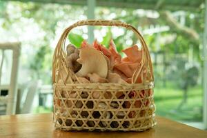 Basket with various kinds of mushrooms inside placed on the table photo