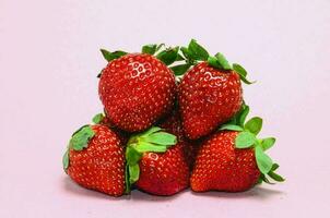 a pile of strawberries on a pink background photo