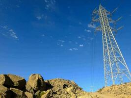 a large electricity tower and rocks in the desert photo