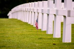 a small american flag is placed in front of a row of white crosses photo