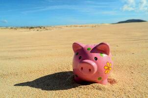 pink piggy bank in the sand photo