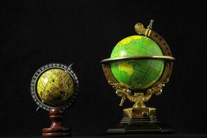 two small globe models on a black background photo