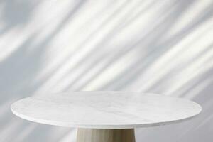 Round marble table top with tree leaves shadow drop on white wall background for mockup product display photo