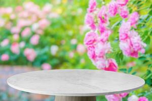 Empty marble table top with blur rose garden background for product display photo
