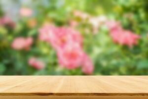 Empty wood table top with blur rose garden background for product display photo