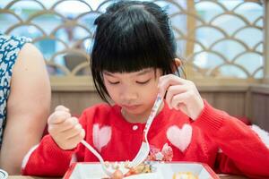 linda pequeño asiático niño niña comiendo comida foto