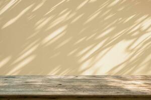 Empty wood table top on beige wall texture with tree leaves shadow background photo