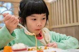 linda pequeño asiático niño niña comiendo comida foto