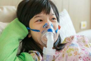 Sick little asian girl inhalation with nebulizer for respiratory treatment photo