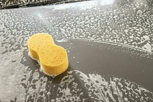 car cleaning and washing with yellow sponge and foam soap photo