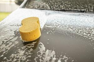 coche limpieza y Lavado con amarillo esponja y espuma jabón foto