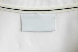 Blank white laundry care clothes label on white shirt fabric texture background photo