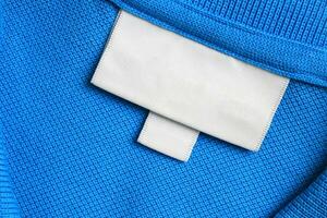 Blank white laundry care clothes label on blue shirt fabric texture background photo