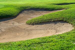 golf curso arena pozo búnkeres, verde césped rodeando el hermosa arena agujeros es uno de el más desafiante obstáculos para golfistas y agrega a el belleza de el golf curso. foto