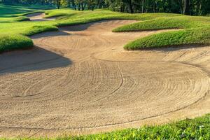 golf curso arena pozo búnkeres, verde césped rodeando el hermosa arena agujeros es uno de el más desafiante obstáculos para golfistas y agrega a el belleza de el golf curso. foto