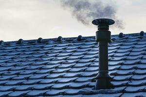 Chimney of a wood or pellet stove installed on the roof with smoke photo