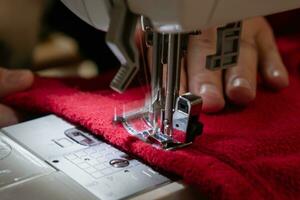 hombre utilizando un de coser máquina con un rojo prenda, para reparar trabajar, personalización, creación, reciclado foto