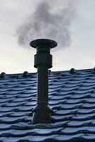 Chimney of a wood or pellet stove installed on the roof with smoke photo