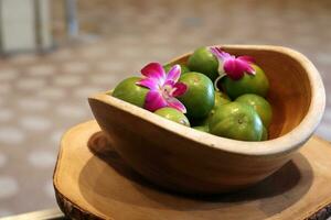 fruit in wooden bowl with pink orchids on table photo