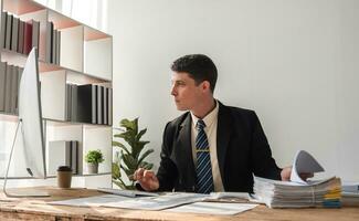 Unhappy young businessman feeling bored and stressed at work looking at laptop with hopeless expression while sitting in office photo