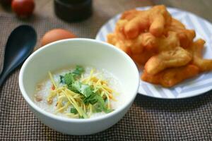 Joke or Congee in a Thai style cup Served on a wooden table. It's an Asian breakfast. photo