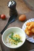 Joke or Congee in a Thai style cup Served on a wooden table. It's an Asian breakfast. photo