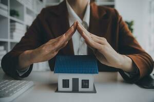 Female hands saving small house with a roof photo