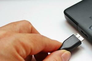 Close up of a man's hand holding a USB flash drive or USB cable 2 photo