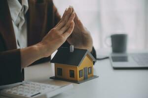 Female hands saving small house with a roof photo