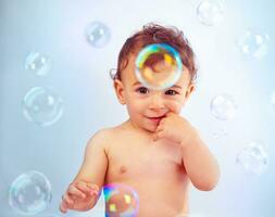 Cute baby boy playing with soap bubbles photo