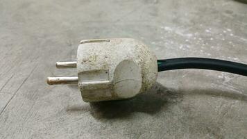 Electric plug on workshop floor. Electric European plug. White power cable with plug. Power cord close-up. photo