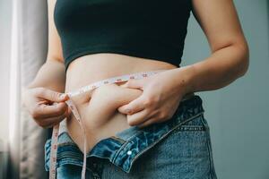 Close up of a belly with scar from c-section and abdominal fat. Women's health. A woman dressed up in sportswear demonstrating her imperfect body after a childbirth with nursery on the background. photo