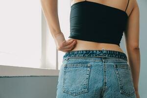 Close up of a belly with scar from c-section and abdominal fat. Women's health. A woman dressed up in sportswear demonstrating her imperfect body after a childbirth with nursery on the background. photo