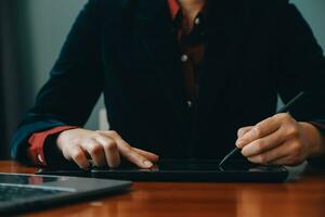 Asian Businesswoman Using laptop computer and working at office with calculator document on desk, doing planning analyzing the financial report, business plan investment, finance analysis concept. photo