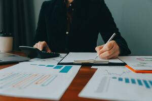 Group of confident business people point to graphs and charts to analyze market data, balance sheet, account, net profit to plan new sales strategies to increase production capacity. photo