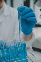 Scientist or medical in lab coat working in biotechnological laboratory, Microscope equipment for research with mixing reagents in glass flask in clinical laboratory. photo