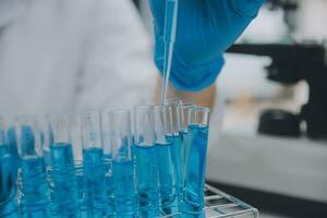 Scientist or medical in lab coat working in biotechnological laboratory, Microscope equipment for research with mixing reagents in glass flask in clinical laboratory. photo