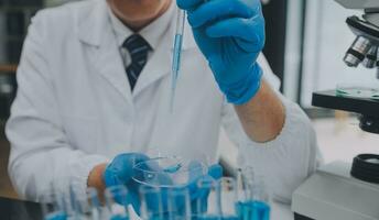 Scientist or medical in lab coat working in biotechnological laboratory, Microscope equipment for research with mixing reagents in glass flask in clinical laboratory. photo